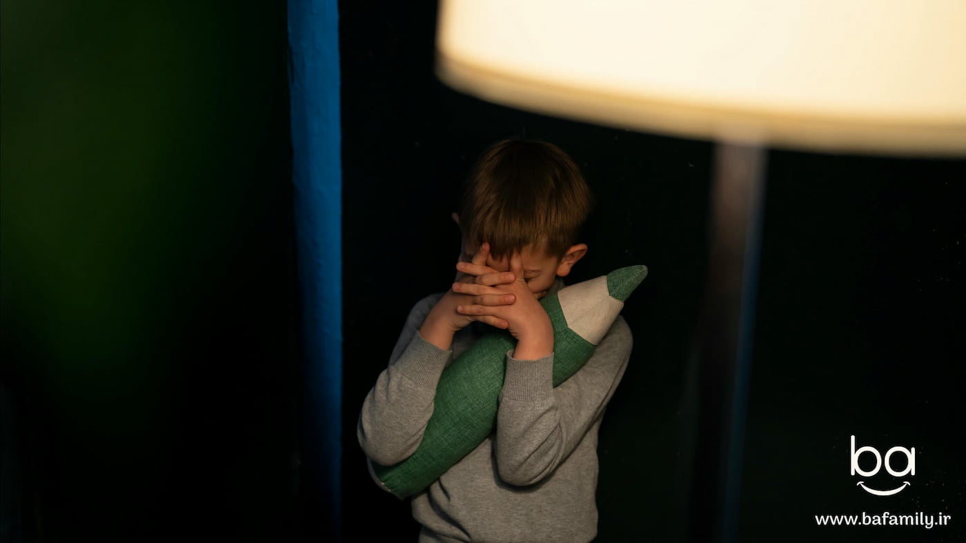 کودک ۳ تا ۵ ساله در اتاق نیمه‌تاریک که از تاریکی می‌ترسد و به دنبال اطمینان از والدین است.