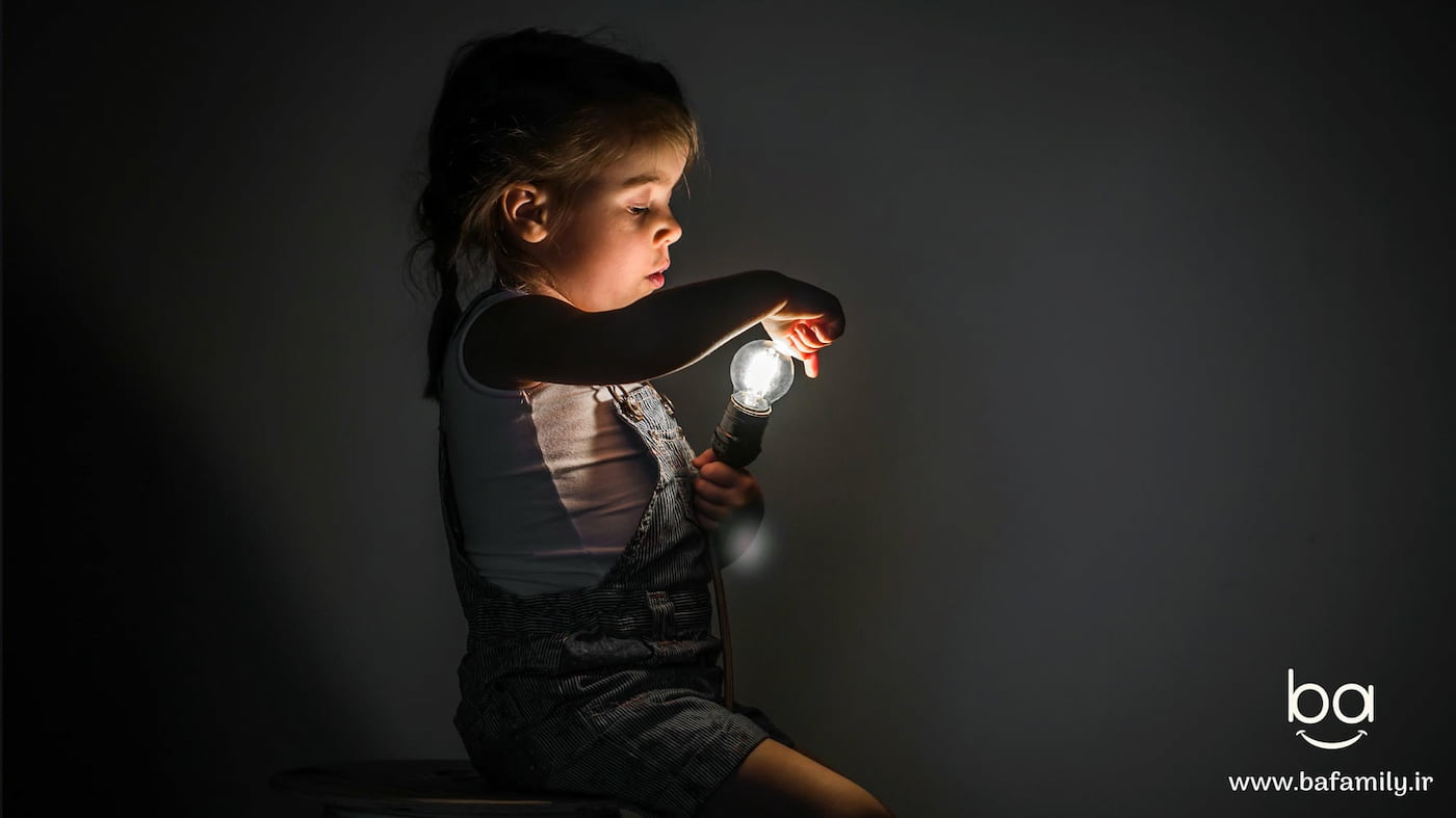 کودکی در اتاق نیمه‌تاریک چراغ خواب را در دست گرفته و با احساس آرامش به نور آن نگاه می‌کند.